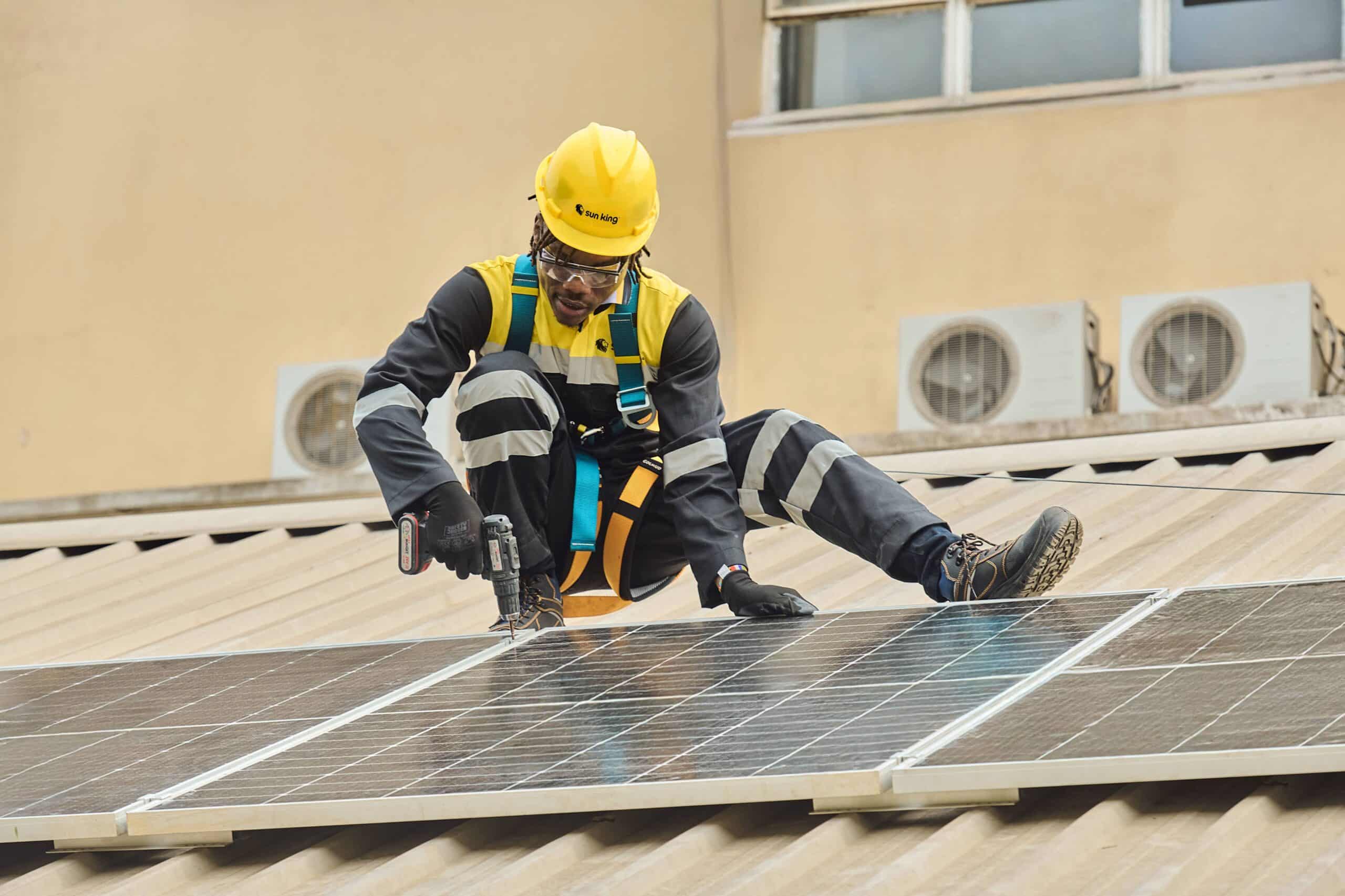 Renewable energy giant, SunKing, worker on a rooftop fixing a solar panel